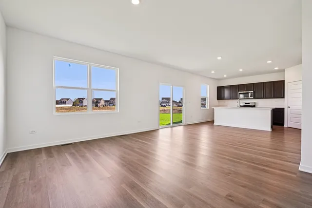 a kitchen with stainless steel appliances granite countertop a refrigerator a stove a sink and a microwave with wooden floor