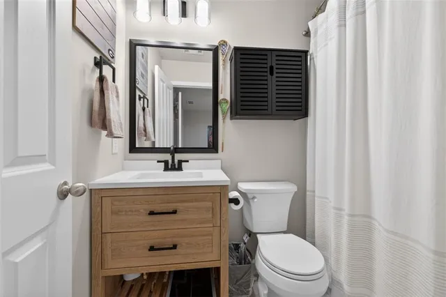a bathroom with a granite countertop toilet a sink and a mirror