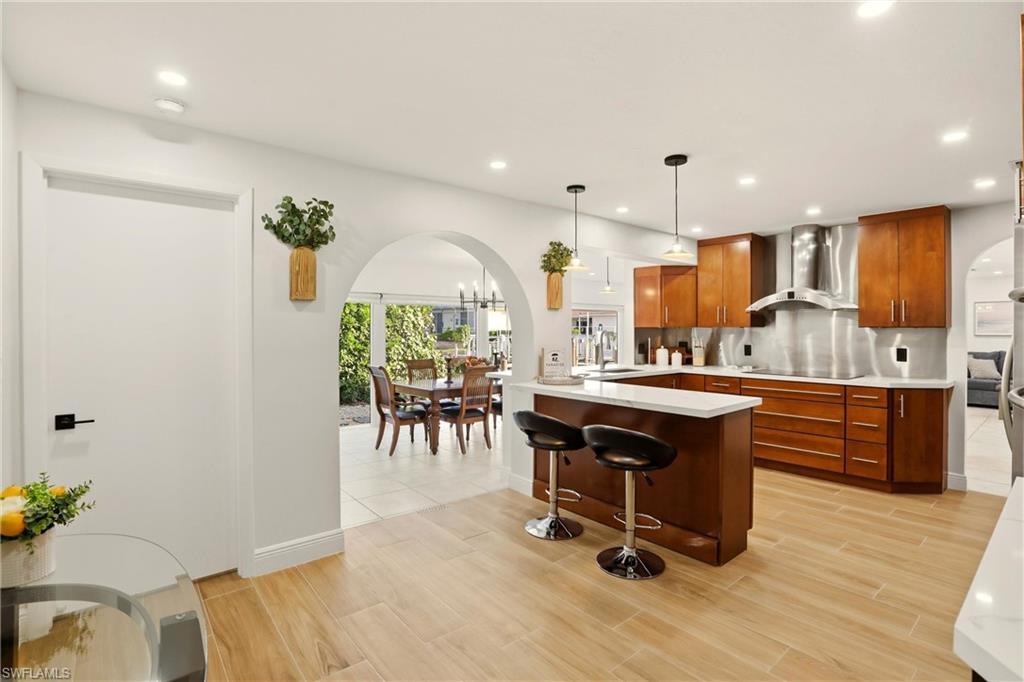 339 Landmark Street Marco Island, FL 34145 - Photo 14 of 50 Kitchen featuring arched walkways, a breakfast bar, a peninsula, pendant lighting, and wall chimney exhaust hood