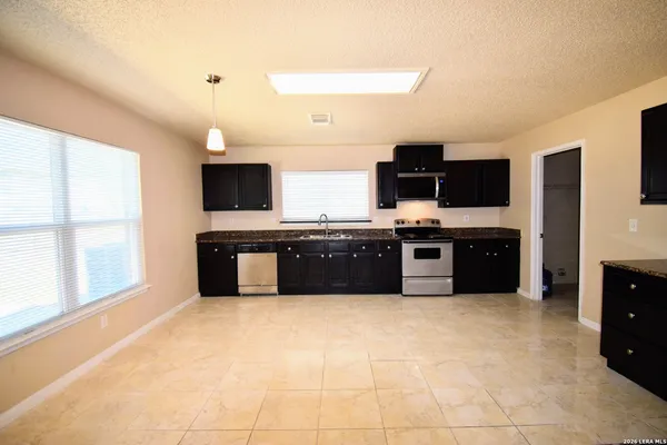 a large kitchen with stainless steel appliances granite countertop a stove refrigerator and a sink