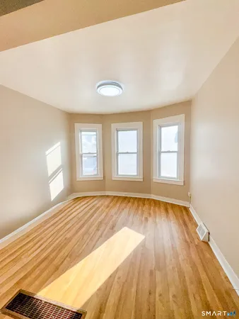 a view of an empty room with wooden floor and a window