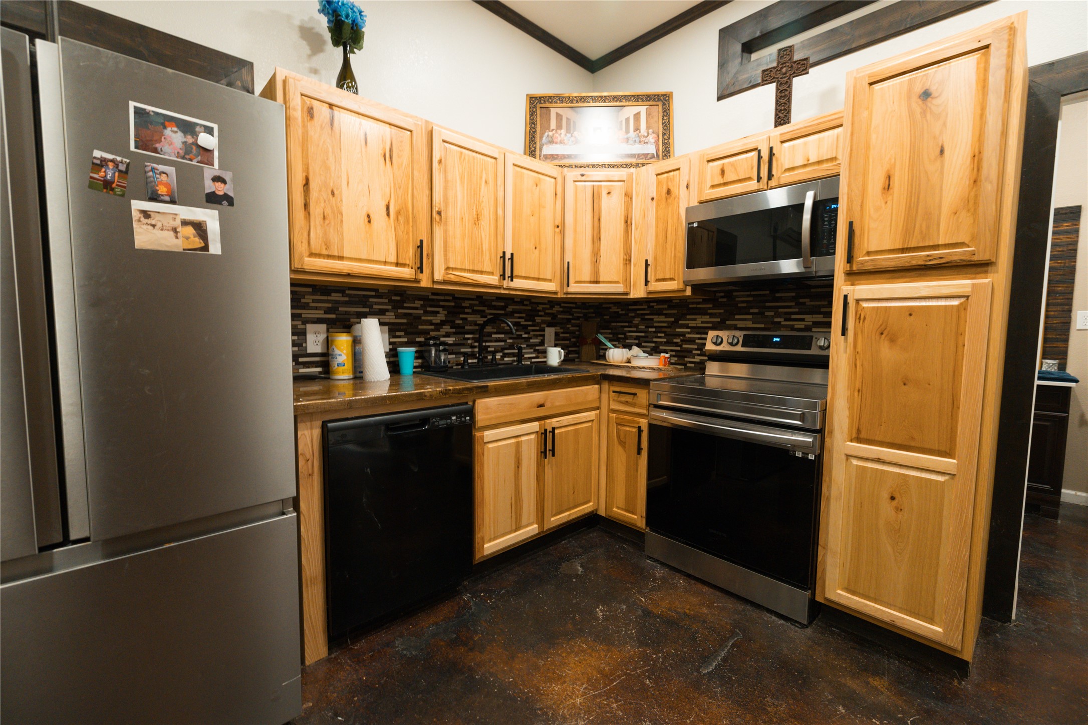 143 County Road Paige, TX 78659 - Photo 32 of 36 Guest house Kitchen featuring appliances with stainless steel finishes, backsplash, dark butcher block countertops, finished concrete floors, and crown molding