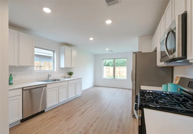 a kitchen with kitchen island white cabinets and wooden floor