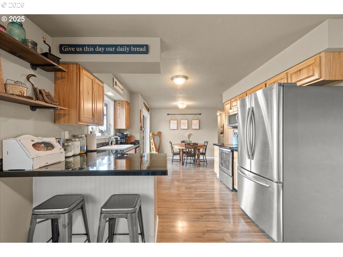 1415 Sightly Road Toutle, WA 98649 - Photo 9 of 36 a kitchen with stainless steel appliances granite countertop a refrigerator a sink a stove and white cabinets with wooden floor