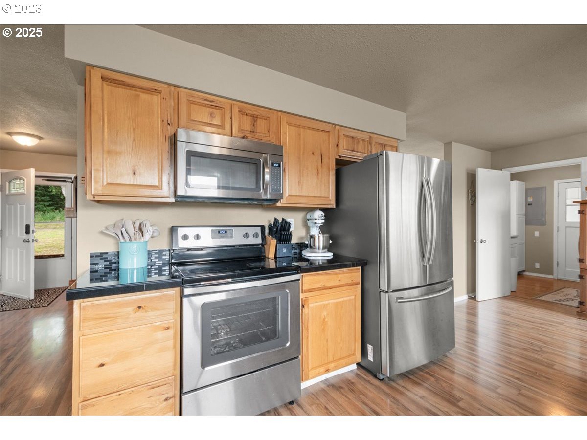 1415 Sightly Road Toutle, WA 98649 - Photo 10 of 36 a kitchen with granite countertop a refrigerator stove and microwave