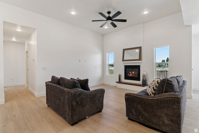 5777 West 4100 South Hooper, UT 84315 - Photo 5 of 41 Living room featuring ceiling fan, light wood finished floors, a glass covered fireplace, recessed lighting, and a high ceiling