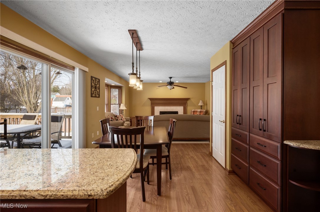 9132 Reed Road North Ridgeville, OH 44039 - Photo 5 of 43 Dining room featuring a tiled fireplace, light wood-style floors, ceiling fan, and a textured ceiling