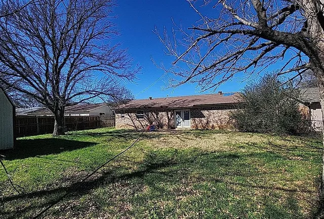 a view of a yard with a table and chairs under an umbrella