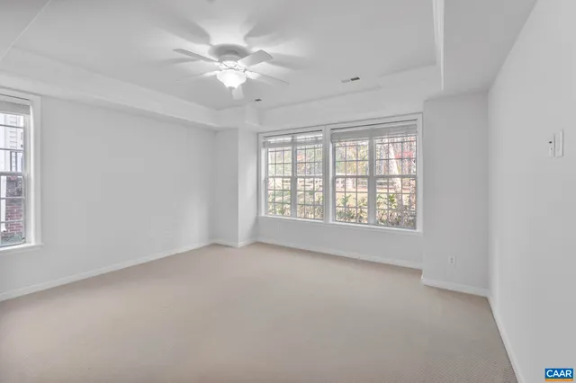 an empty room with windows and fan