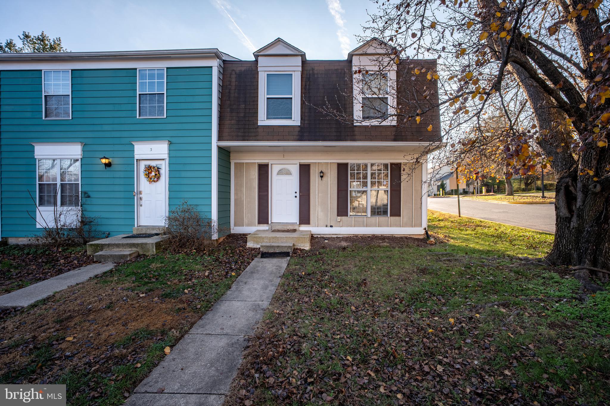 a view of a brick house with a yard and large tree