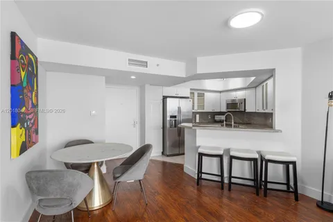 a kitchen with stainless steel appliances granite countertop a dining table chairs and a refrigerator