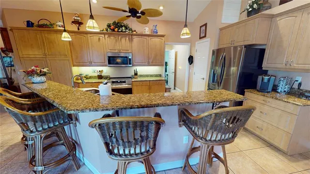 a kitchen with granite countertop a table chairs stove and refrigerator