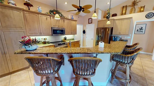 a kitchen with stainless steel appliances kitchen island granite countertop a dining table chairs and a refrigerator