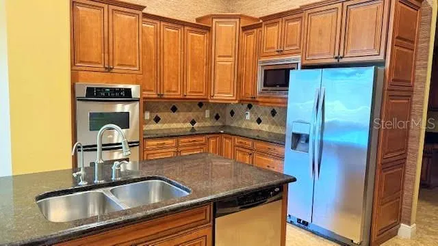 a kitchen with stainless steel appliances granite countertop a refrigerator a sink and dishwasher