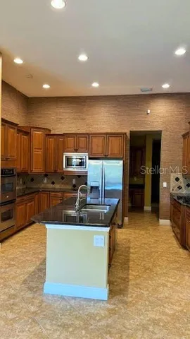 a kitchen with stainless steel appliances granite countertop a sink a stove top oven a counter space and cabinets