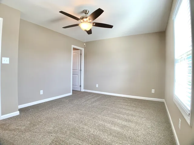 an empty room with a window and a fan