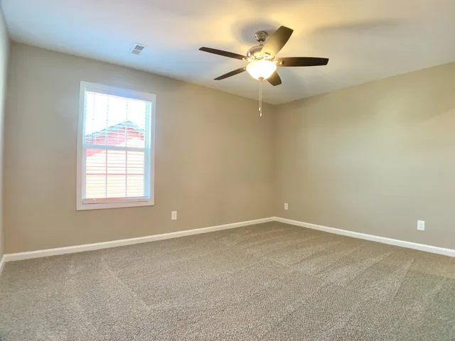 an empty room with a window and a chandelier fan