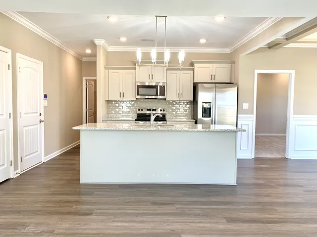 a view of kitchen with stainless steel appliances granite countertop a stove a sink a refrigerator and white cabinets with wooden floor