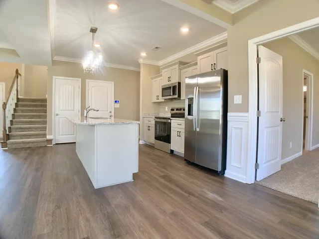 a kitchen with stainless steel appliances a refrigerator a sink and wooden floor