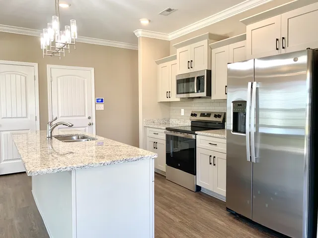 a kitchen with stainless steel appliances granite countertop a refrigerator stove top oven and sink