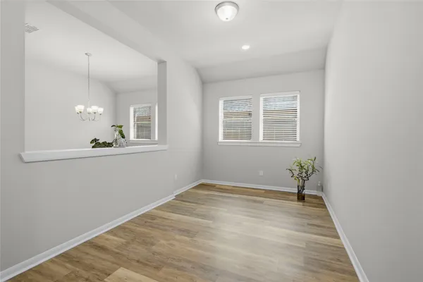 an empty room with wooden floor chandelier fan and windows