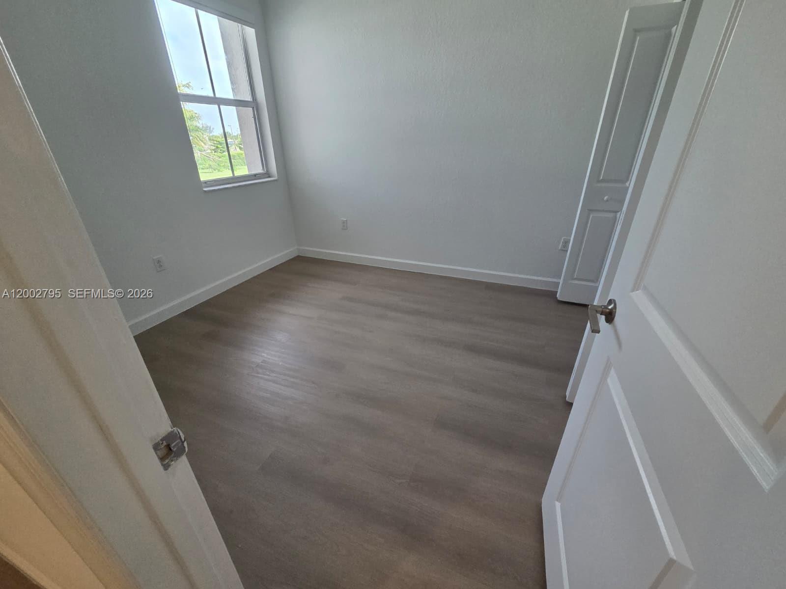 1844 Southeast 27th Street Homestead, FL 33035 - Photo 12 of 23 an empty room with wooden floor and windows
