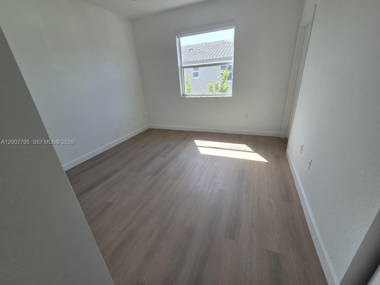 1844 Southeast 27th Street Homestead, FL 33035 - Photo 17 of 23 an empty room with wooden floor and windows