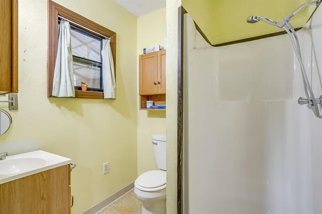 a bathroom with a granite countertop sink mirror vanity and toilet