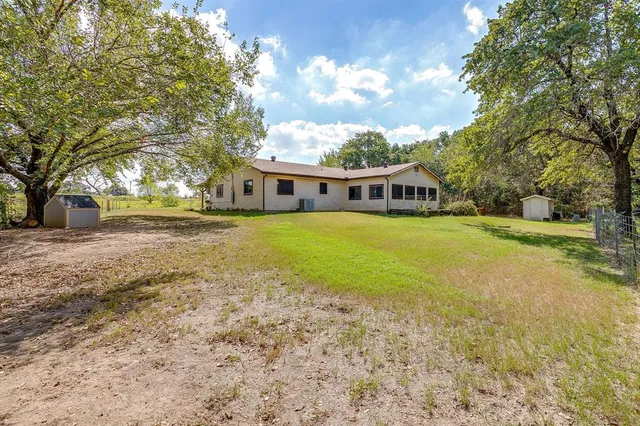 a view of a house with a big yard and large trees