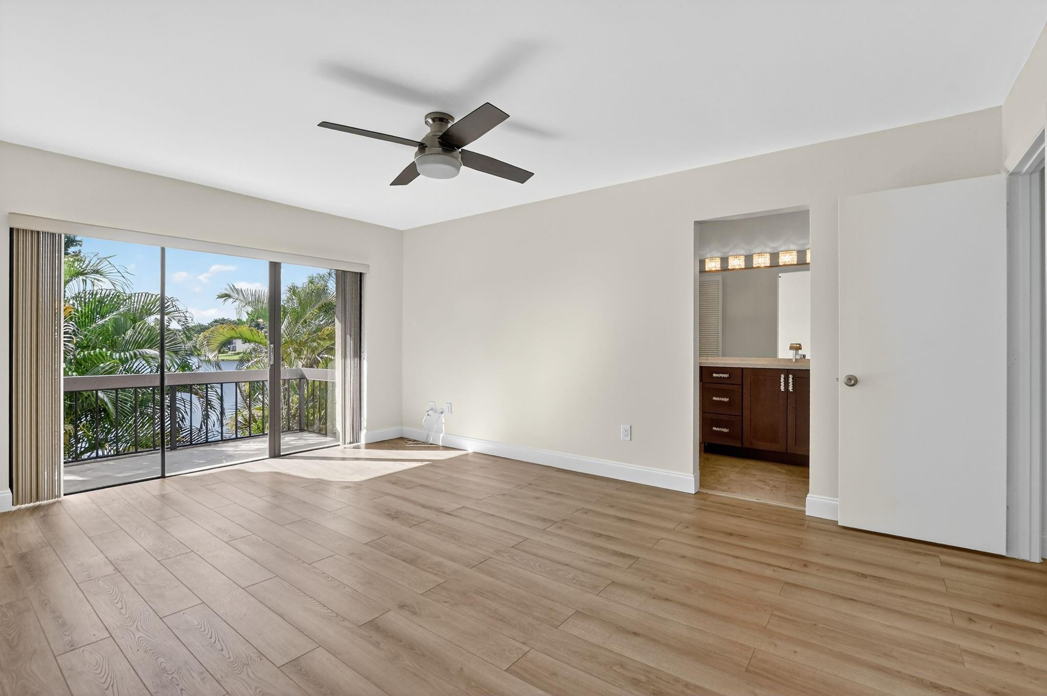 21476 Juego Circle, Unit 8C Boca Raton, FL 33433 - Photo 26 of 54 a view of an empty room with wooden floor and a window