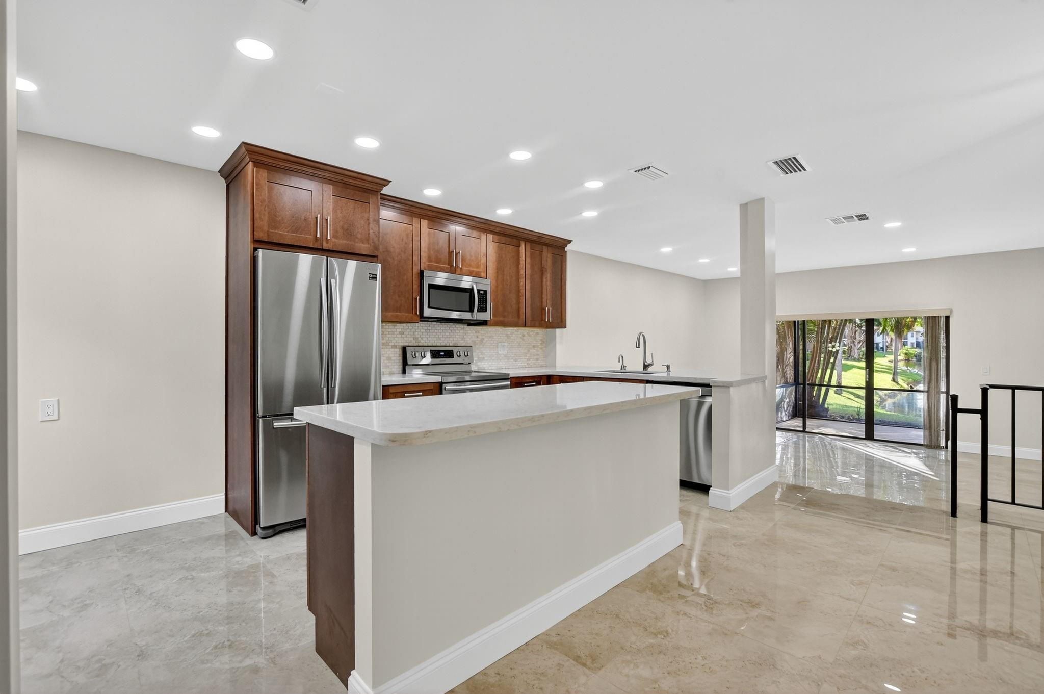 21476 Juego Circle, Unit 8C Boca Raton, FL 33433 - Photo 3 of 54 a view of kitchen with stainless steel appliances refrigerator stove microwave and cabinets