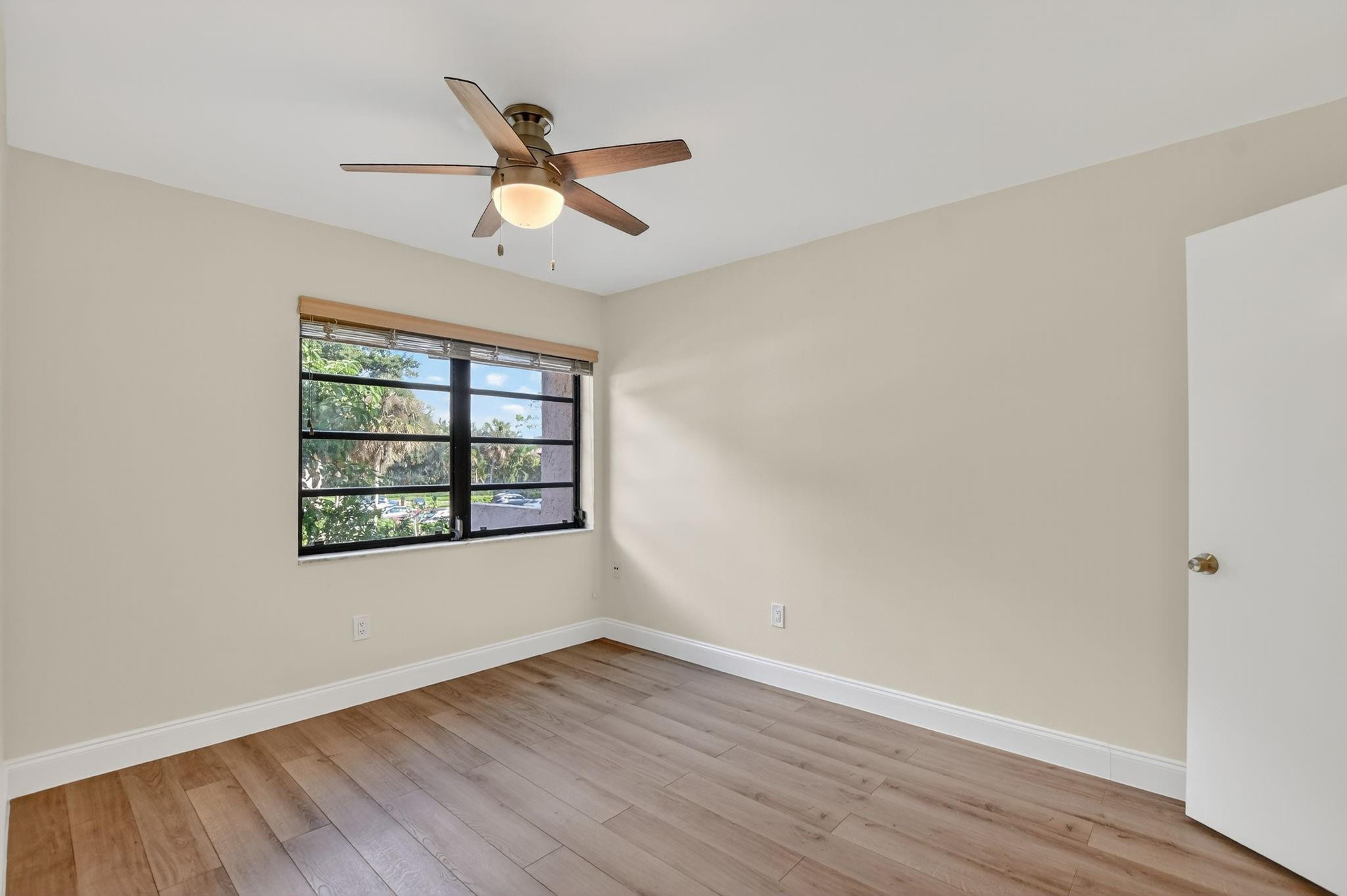 21476 Juego Circle, Unit 8C Boca Raton, FL 33433 - Photo 33 of 54 an empty room with wooden floor ceiling fan and windows