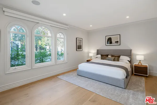 a bedroom with a bed a painting on the wall and a potted plant