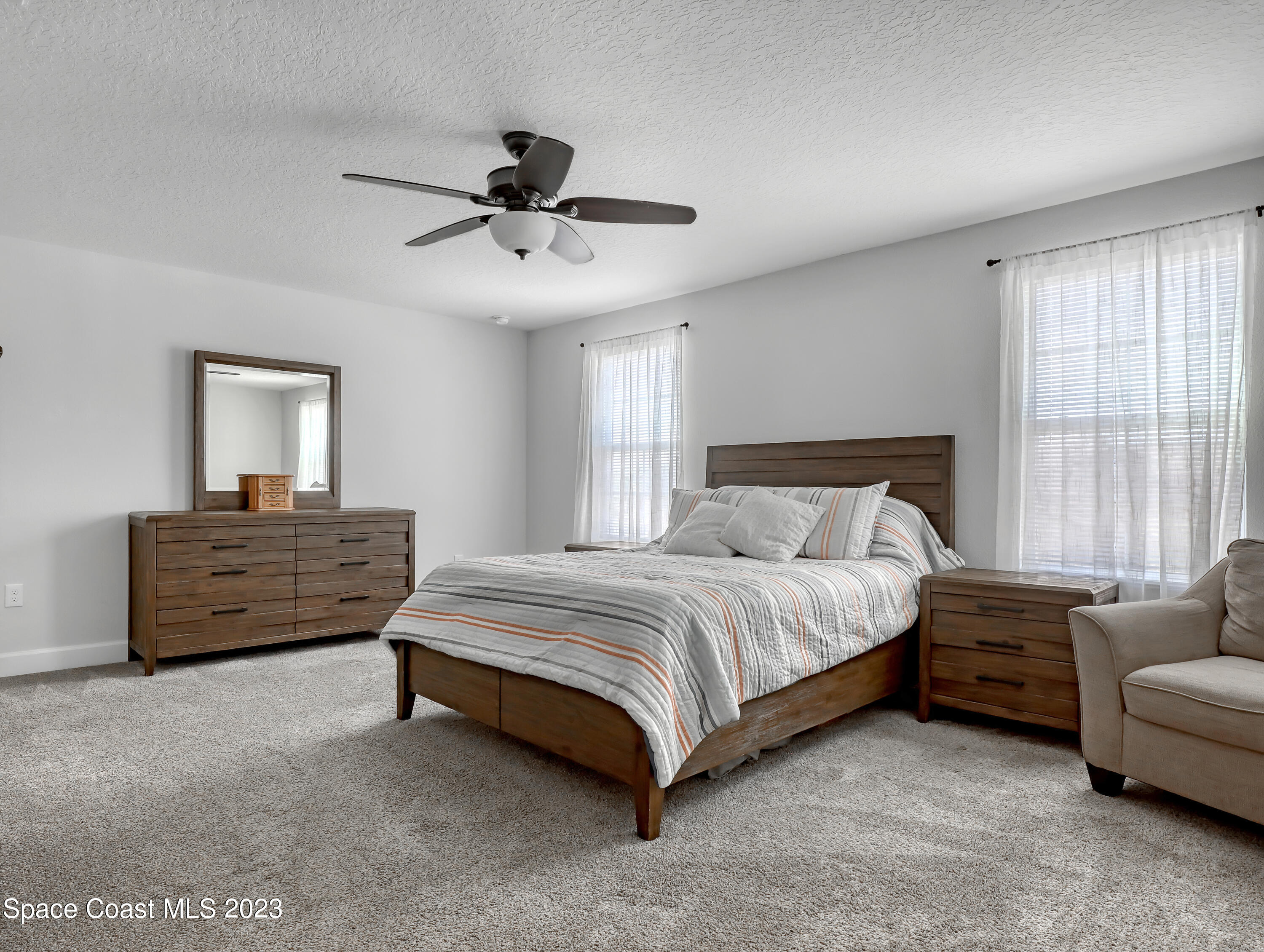 1807 Elkins Point Melbourne, FL 32935 - Photo 22 of 52 a spacious bedroom with a bed a couch and a window