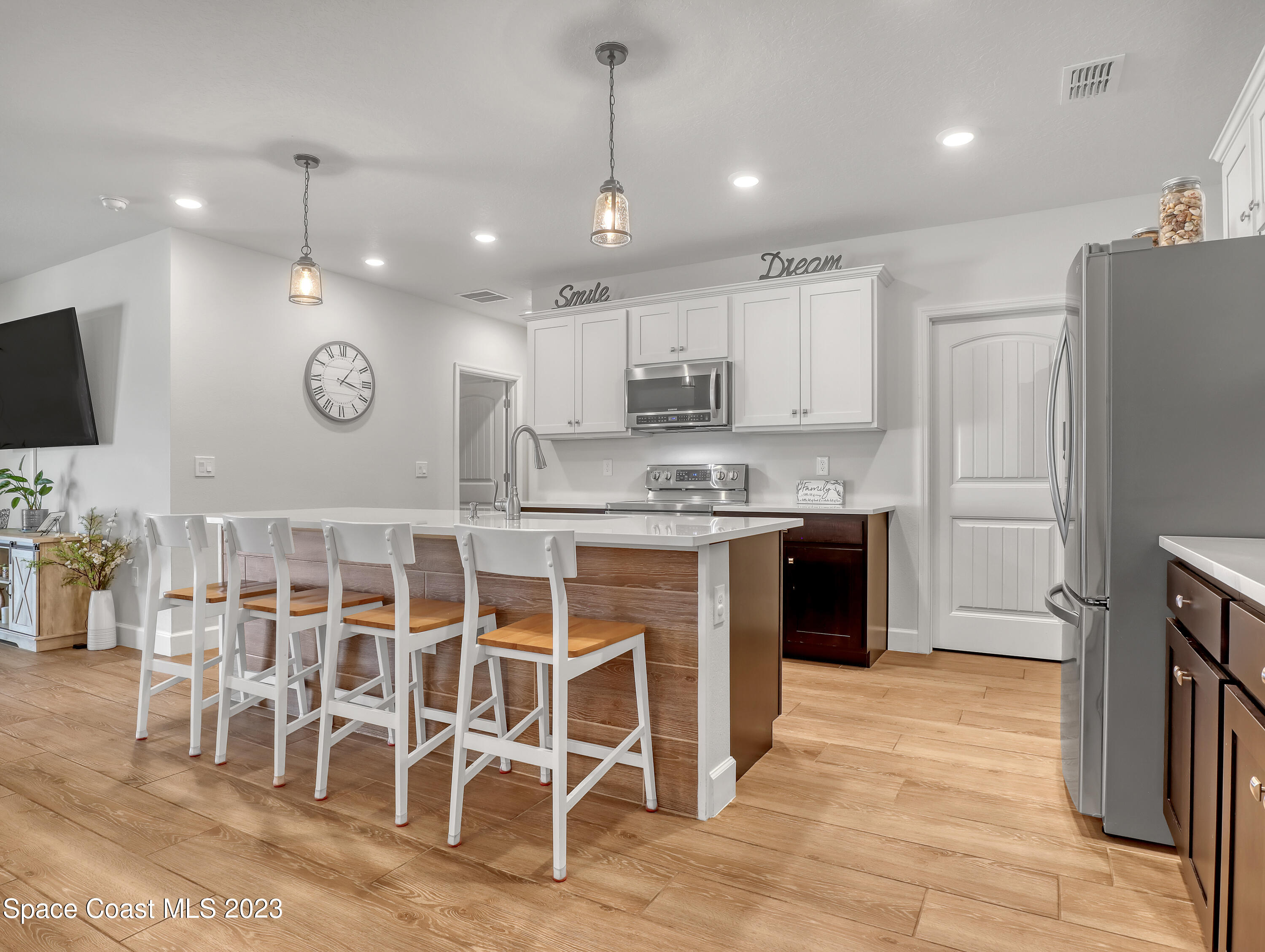 1807 Elkins Point Melbourne, FL 32935 - Photo 9 of 52 a kitchen with stainless steel appliances kitchen island granite countertop a refrigerator a stove a microwave oven a sink with island and chairs in it