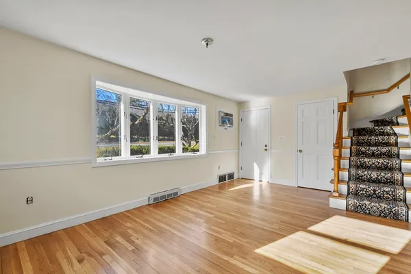 a view of an empty room with wooden floor and windows