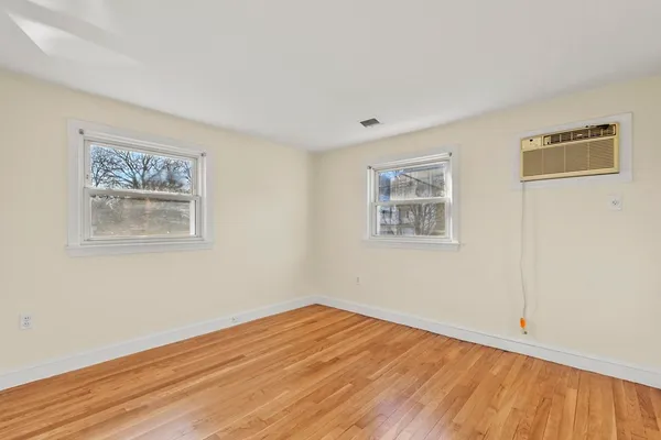 a view of empty room with wooden floor and fan