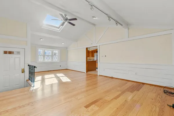 a view of empty room with wooden floor and fan