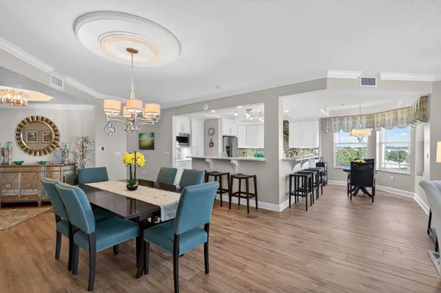 a dining room with wooden floor a chandelier a glass table and chairs
