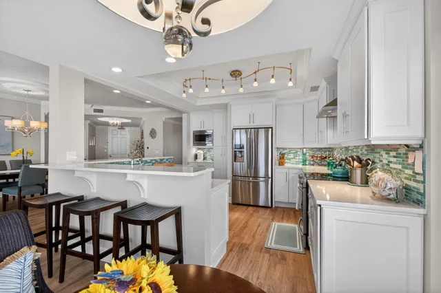 a kitchen with granite countertop a refrigerator a stove a sink dishwasher a dining table and chairs with wooden floor