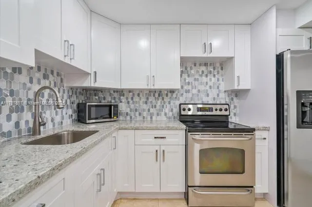 a kitchen with granite countertop a sink stove and refrigerator