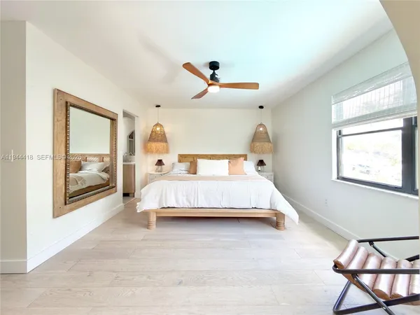 a bedroom with a bed a large mirror and a large window