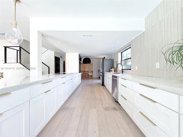 a large white kitchen with cabinets a sink and appliances