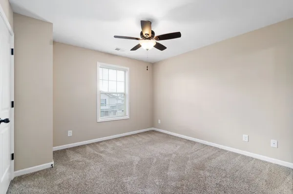 an empty room with a window and a fan