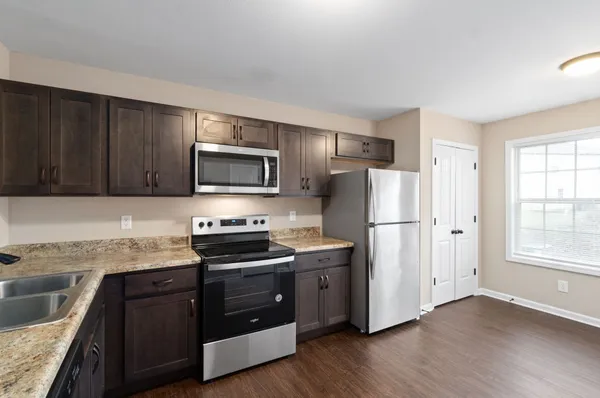 a kitchen with stainless steel appliances granite countertop a refrigerator stove a sink dishwasher and microwave with wooden floor