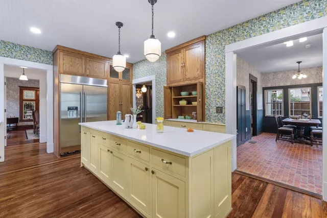 an open kitchen with wooden floor and large windows