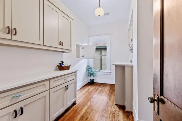 a kitchen with white cabinets and wooden floor
