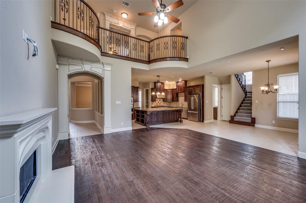 Unfurnished living room with a ceiling fan, a chandelier, a fireplace, stairway, and a high ceiling