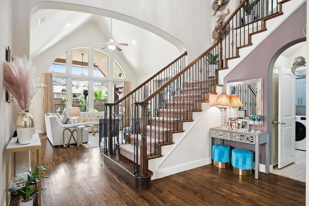 8268 Kara Creek Road Frisco, TX 75036 - Photo 3 of 31 Grand entryway featuring a sweeping staircase with wrought iron balusters and wood handrails, wood-finish flooring, a vaulted ceiling, and an arched window wall