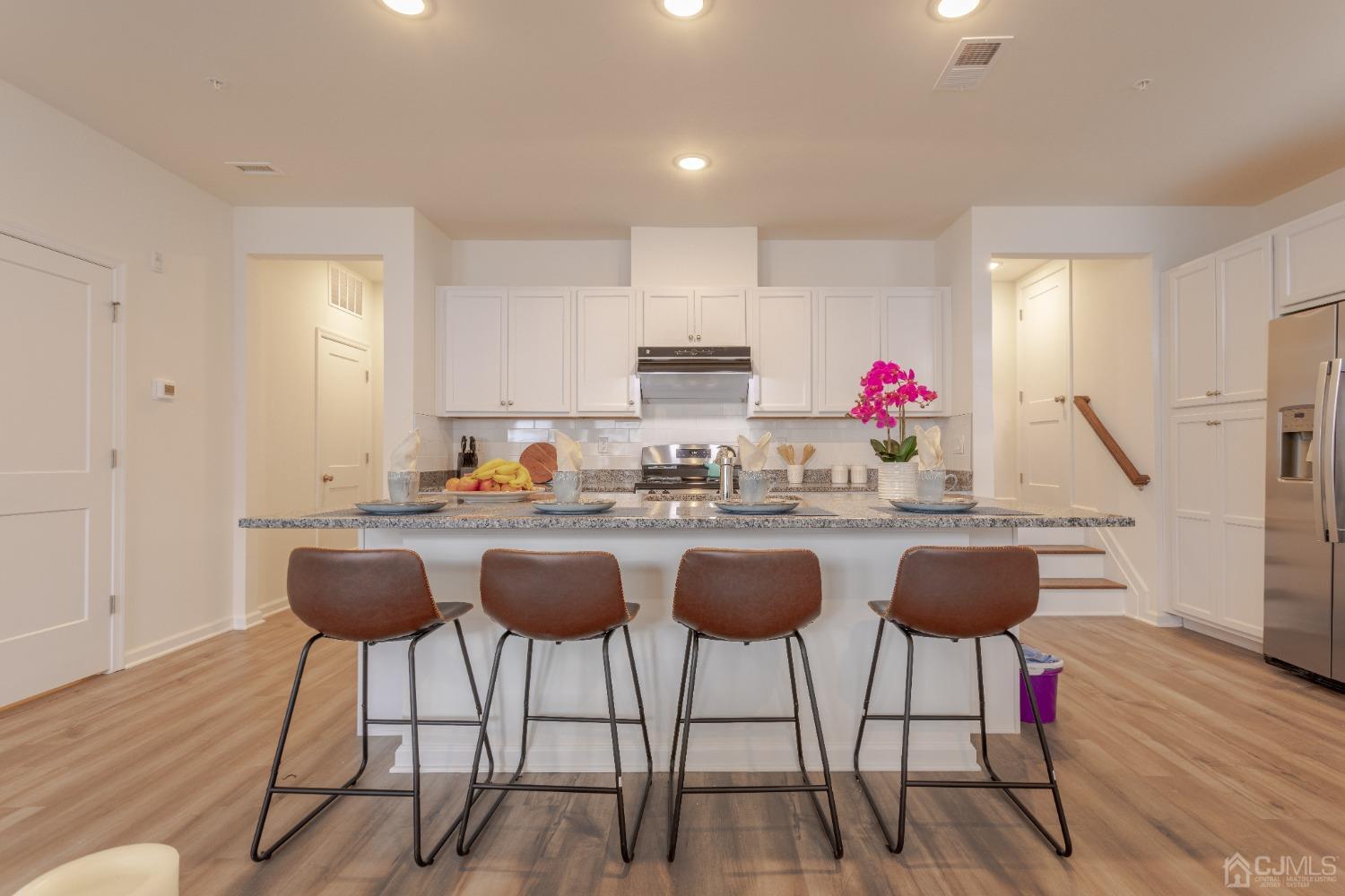a kitchen with granite countertop a dining table chairs and wooden floor